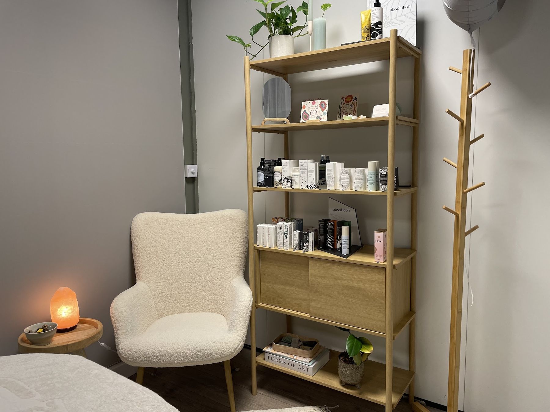 Lounge-hoek met een zachte fauteuil, zoutlamp en een kast met Absolution-producten